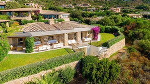 Une villa de style méditerranéen, dotée d’un toit recouvert de tuiles en terre cuite, d’un patio abrité avec des meubles d’extérieur et d’un jardin luxuriant.