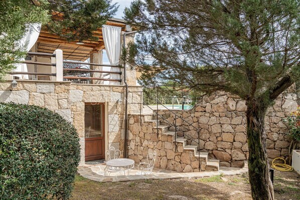 A stone house with a wooden staircase leading to a balcony. - Villa Flor de Lis: Private swimming pool in Punta Molara, 600 meters from the beach. SARDINIA UN... (Isola Molara)