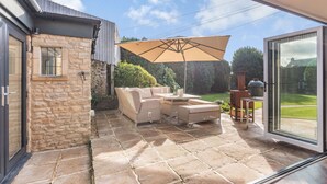 A patio with stone flooring, wicker furniture, and a barbecue grill.