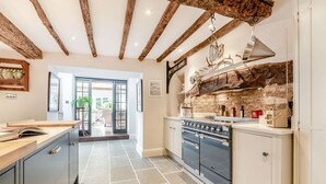 A kitchen with a stone wall, wooden beams, and a sign reading "The Kings Arms".