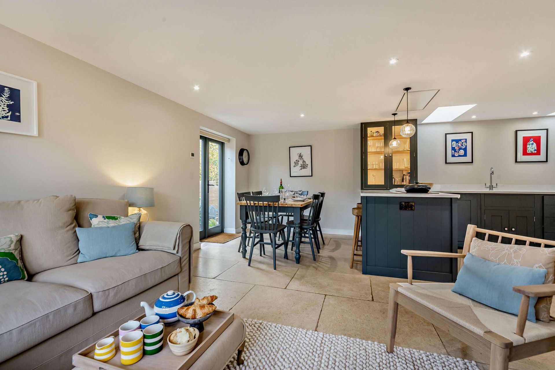A modern living room with a sofa, a dining table, and a kitchen area with a bar.