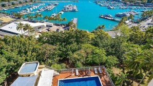 A resort with a large swimming pool, multiple boat docks, and lush greenery.