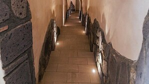 A stone-walled corridor with a tiled floor leading to a distant archway.