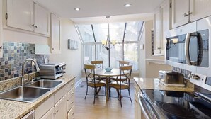 A modern kitchen with a dining area, featuring a large window, stainless steel appliances, and a granite countertop.
