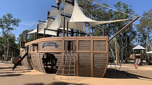 Une structure de jeu sur le thème des pirates, avec un gouvernail de bateau, une échelle et un toboggan.