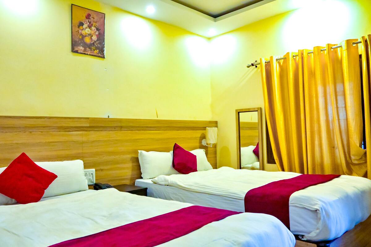 A hotel room with two beds, each with white linens and red pillows, a wooden headboard, a painting on the wall, and a mirror.