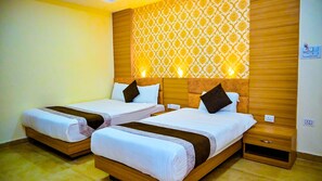 A hotel room with two single beds, wooden headboards, a patterned wall, and a small wooden cabinet. - Hotel Star Holiday (Siddharthanagar)