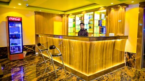 A reception area with a Coca-Cola refrigerator, a counter with shelves of bottled water, and two chairs in front. - Hotel Star Holiday (Siddharthanagar)