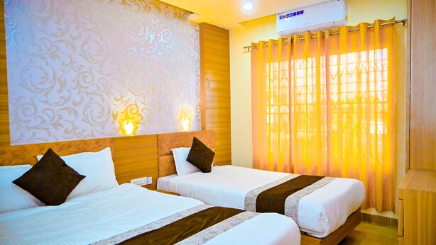 A hotel room with two beds, a wooden headboard, patterned wallpaper, a wall-mounted air conditioner, and a window with curtains. - Hotel Star Holiday (Siddharthanagar)