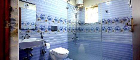 A bathroom with a glass shower enclosure, a toilet, a sink, and a mirror.