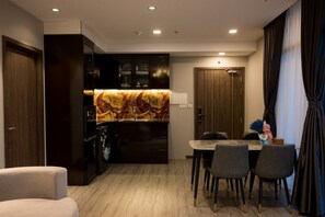 A modern kitchen with dark cabinetry, a marble backsplash, and a dining area with a table and chairs.