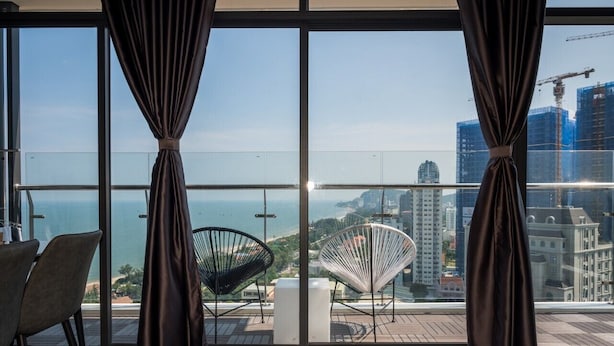 Ein modernes Zimmer mit großen Fenstern, Stadtblick und zwei originellen Stühlen.