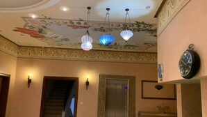 Una hall con pavimento in marmo, una scala, un ascensore e orologi a muro.