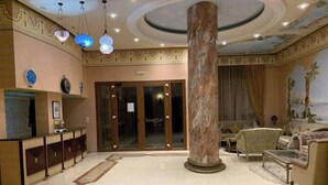 Una hall con una colonna in marmo, una reception e un'area salotto con divani e tavolino.