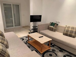 Un salon avec un canapé, une table basse et un téléviseur.