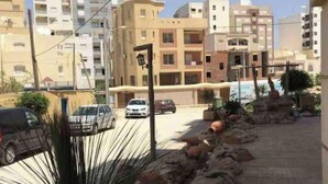 Un quartiere residenziale con palazzi moderni, un vialetto lastricato e alcune auto parcheggiate.