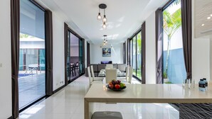 A modern dining area with a long table, a bowl of fruit, and a bench. - 4 Bedroom Modern Pool Villa BL10 (Hua Hin)