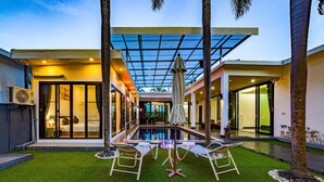 A modern house with a swimming pool, outdoor seating, and a covered patio area. - 4 Bedroom Modern Pool Villa BL10 (Hua Hin)