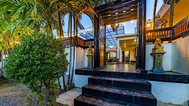 A staircase leading to a covered area with a glass ceiling, surrounded by greenery and decorative statues. - 4 Bedroom Modern Pool Villa BL10 (Hua Hin)