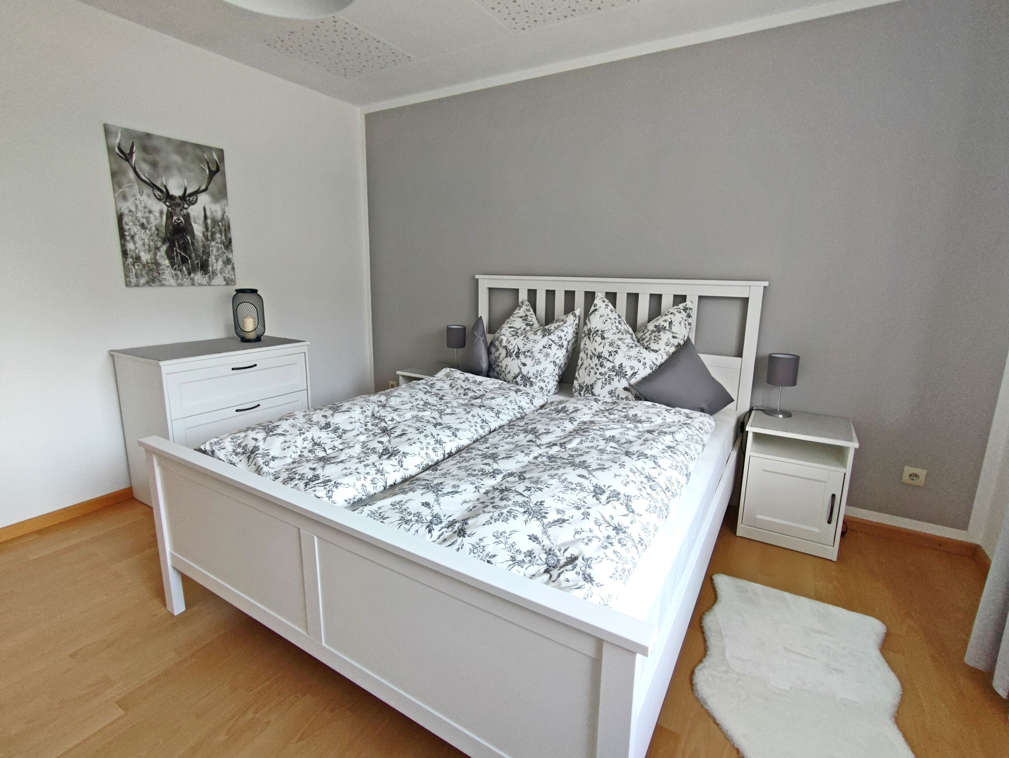 Une chambre à coucher avec un lit, des tables de chevet, une lampe, un tapis et un tableau au mur.