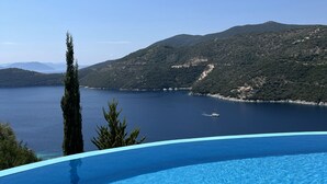Un ciel d’un bleu éclatant, une piscine et une vue sur un lac avec des montagnes en arrière-plan.