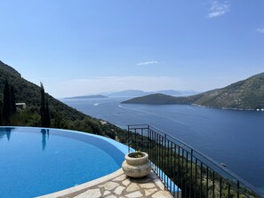 Ein Pool mit Blick auf ein großes Gewässer und Hügel.