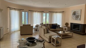 Un salon spacieux comprenant un canapé, des fauteuils, une table basse et une cheminée.