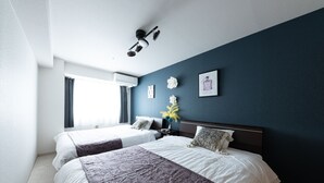 A hotel room with two beds, a ceiling fan, an air conditioning unit, a window with curtains, and a wall-mounted picture. - AMS TOWER (Sapporo)