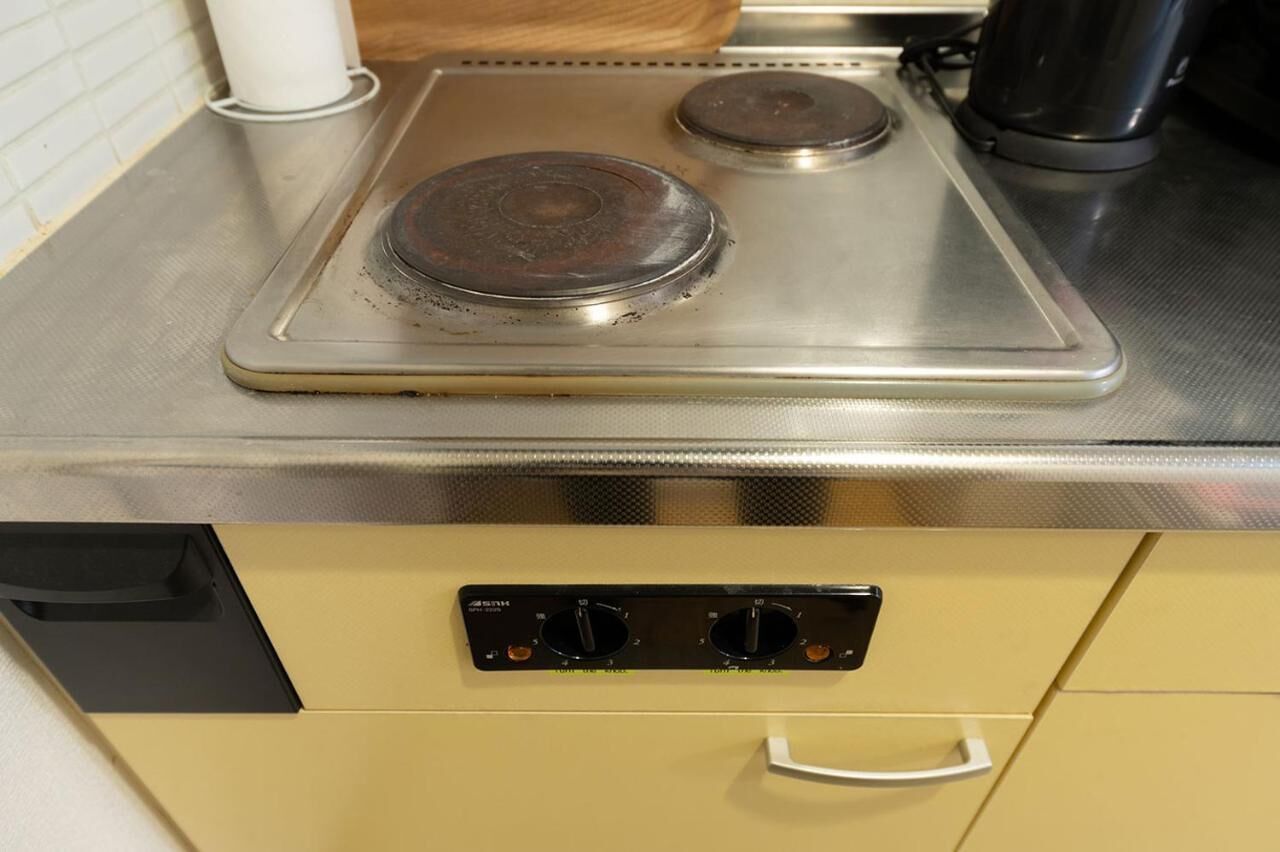 A kitchen with a stainless steel stove, a control panel with knobs, and a black coffee maker.