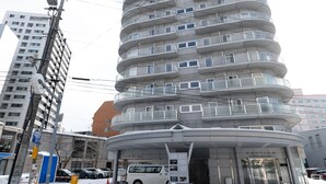 A tall, cylindrical hotel with multiple balconies and a modern architectural design. - AMS TOWER (Sapporo)