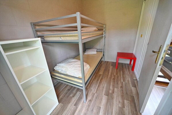 Dormitorio con literas, un banco rojo y una estantería blanca.