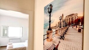 Une chambre d’hôtel avec un lit, une fenêtre et un tableau représentant un paysage de bord de mer.