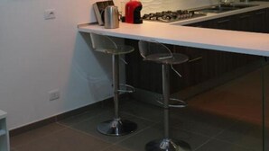 Une cuisine moderne dotée d’un îlot central, de tabourets de bar, de luminaires suspendus et d’une œuvre d’art représentant un paysage urbain accrochée au mur.