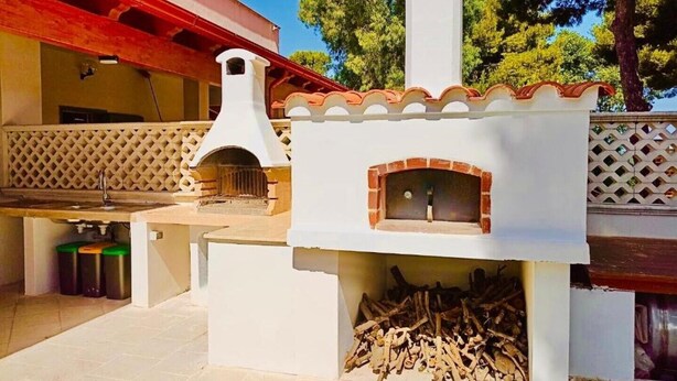 Un four à pizza extérieur doté d’une cheminée, d’un foyer et d’une pile de bûches.