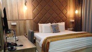 Una habitación de hotel con una cama grande, un escritorio con teléfono y una televisión.