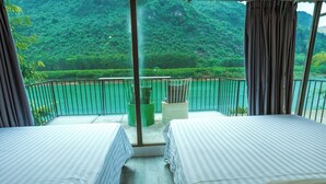 A balcony with two beds, a view of a green forest, and a railing. - A Little Leaf Homestay  (Phong Nha)