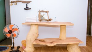 A wooden table with a rustic design, a small shelf, and a decorative item on top. - A Little Leaf Homestay  (Phong Nha)