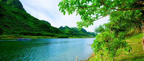 A river with a boat, surrounded by lush greenery and hills.