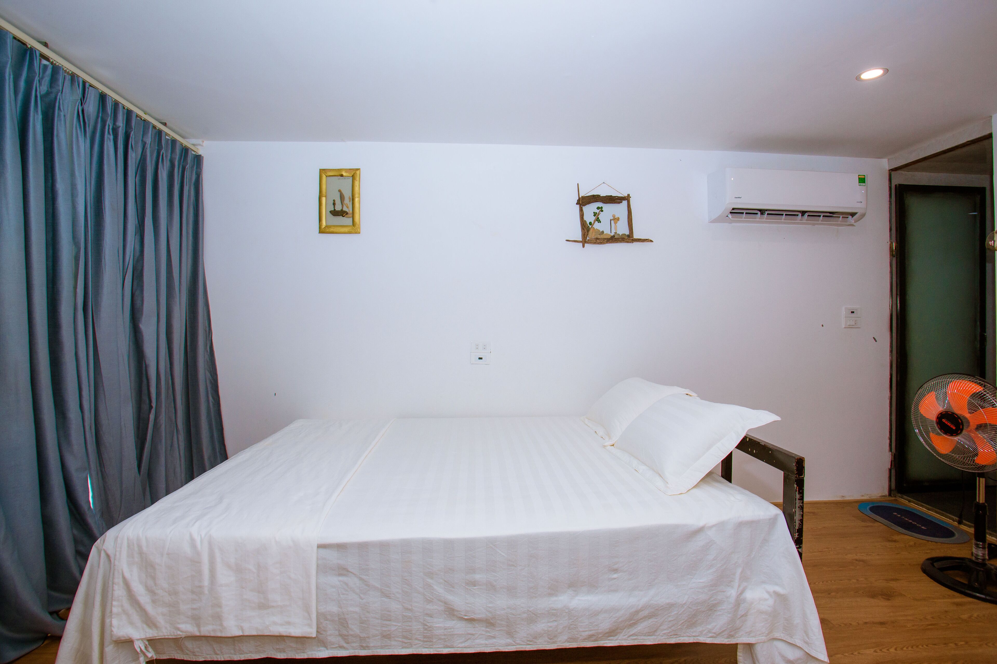 Ein Schlafzimmer mit einem Bett, einer Wand-Klimaanlage und einem Deckenventilator.