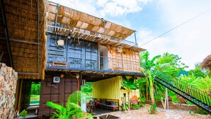 A two-story building with a balcony, a thatched roof, and a stone pathway leading to the entrance. - A Little Leaf Homestay  (Phong Nha)