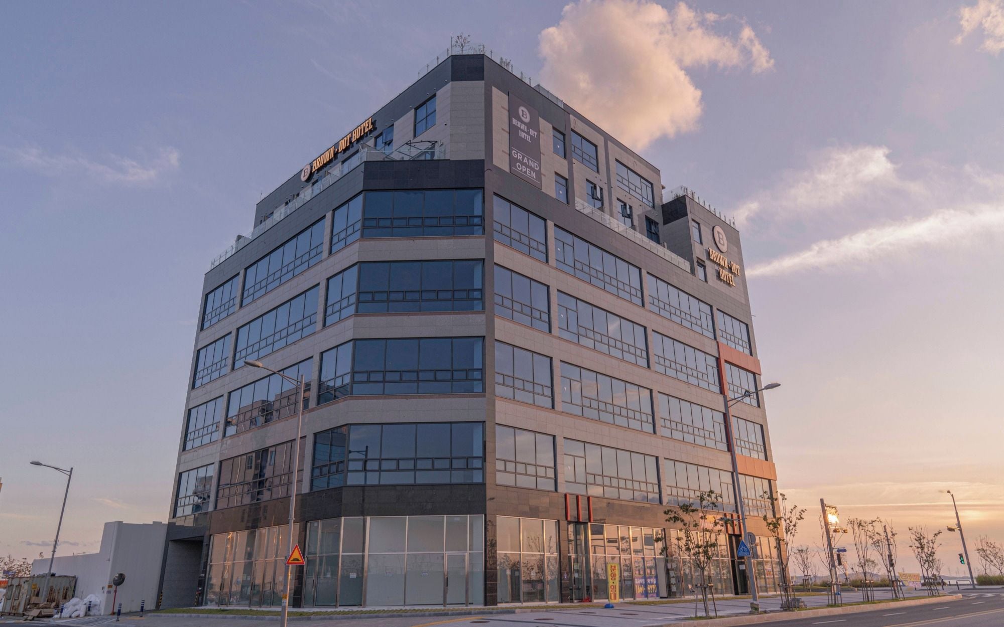 A multi-story hotel with a modern architectural design, featuring large windows and a prominent signage indicating 'BROWN DOT HOTEL.'