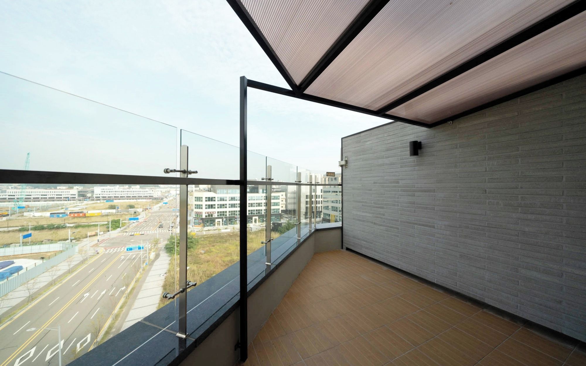 Un balcón con vistas a un paisaje urbano, una puerta de cristal y una pared de ladrillo.