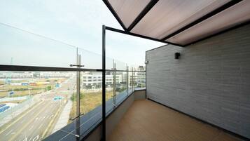 Un balcón con vistas a un paisaje urbano, una puerta de cristal y una pared de ladrillo.