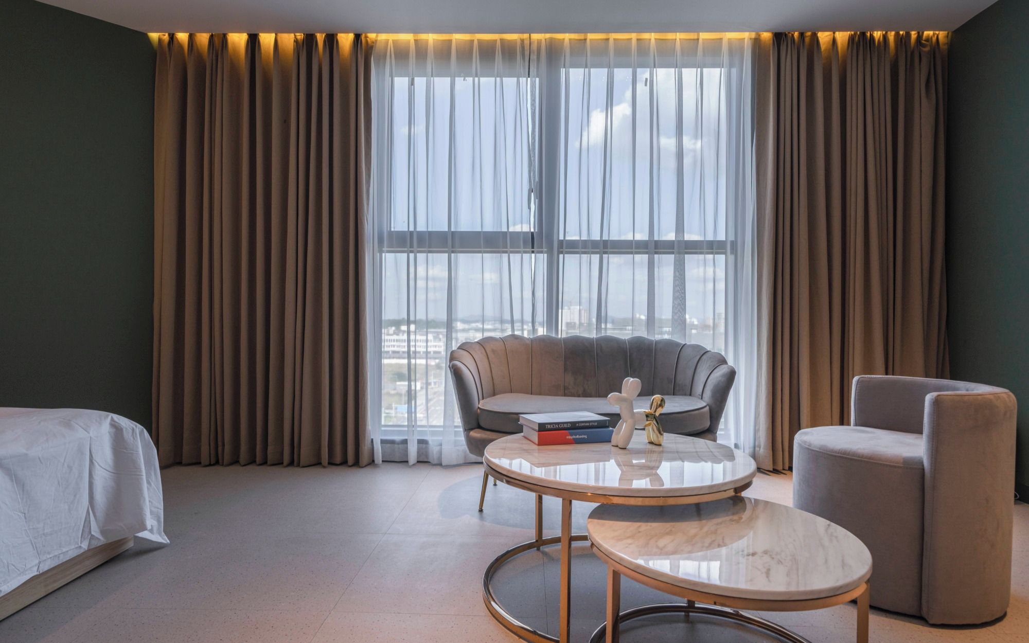 A hotel room with a bed, a round table with a book, a chair, and a sofa.