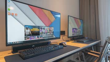 Two monitors on a desk with a keyboard and mouse, and a chair with a tray.