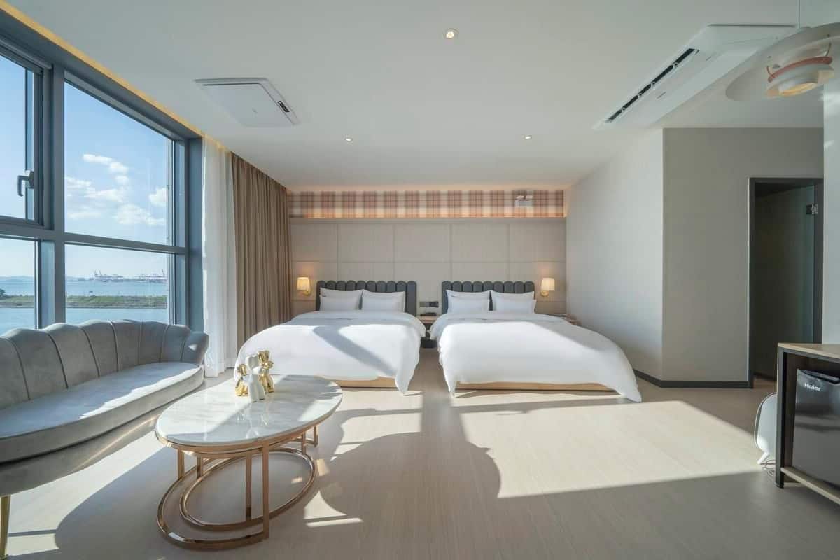 A hotel room with two beds, a sofa, a small table, and a TV.