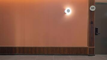A wall with a circular light fixture and a door with a number plate.