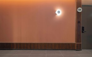 A wall with a circular light fixture and a door with a number plate. - Brown Dot Geobuksum (Siheung)