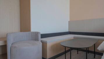 Una zona de estar con un banco y una mesa redonda, suelo de madera y una pared con panel vertical de madera.