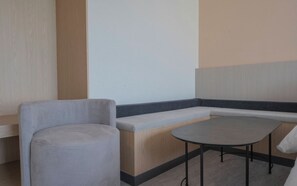 A seating area with a bench and a round table, a wooden floor, and a wall with a vertical wooden panel. - Brown Dot Geobuksum (Siheung)